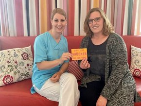 Postkartenaktion (© Stephanie Seckel) Das Foto zeigt die onkologische Fachkrankenschwester Michaela Winhart (rechts) und die Stationsleiterin Julia Rinkl, die bei onkologischen Pflegevisiten die mutmachenden Postkarten an Krebspatientinnen verteilen.