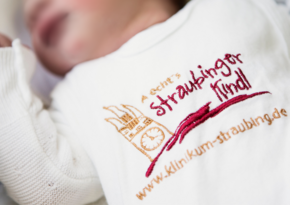 Förderung Geburtshlilfe (© Johannes Lehner) Bild von einem Baby Im Strampler mit Aufschrift Straubinger Kindl