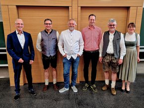 Anästhesie Fortbildung (© Alexandra Marquardt) Vor einem Holzpanell zum Teil in Tracht (zwei rechts und zweiter von links) . Der Herr links in ANzug und in der MItte die beiden in Hemd und Jeans.