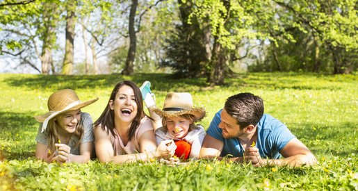 Familie (© Fotowerk/ Fotolia) Foto einer Familie auf der Wiese liegend