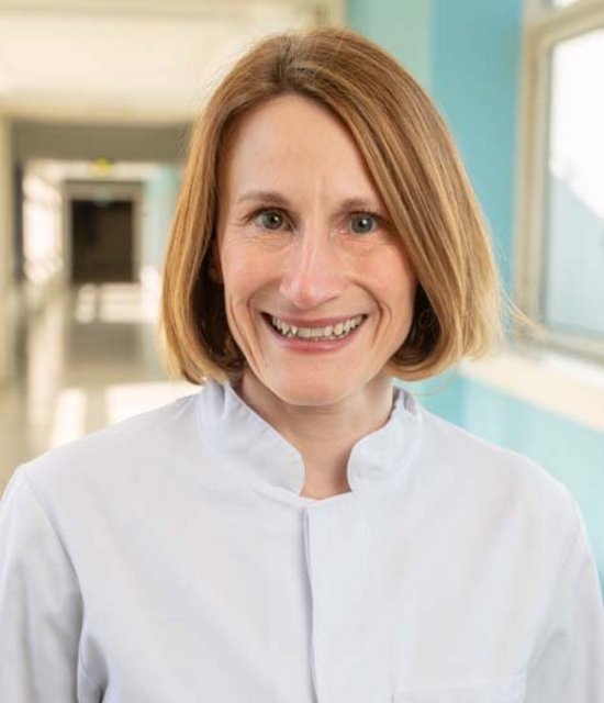 Priv. Doz. Dr. Lisa Geis (© Johannes Lehner) Dame mit dunkelblondem Bob, lachend in einem Krankenhausflur