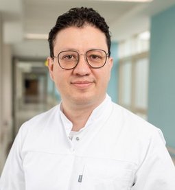 Carlos Andres Conejo Gonzales (© Johannes Lehner) Junger Arzt mit Brille, hellhäutig, schwarzes kurzes Haar, kurzer Arztkittel