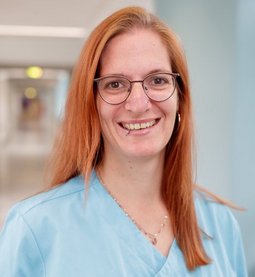 Claudia Zink (© Johannes Lehner) Lange rötliche Haare und Brille, türkiser Kasack