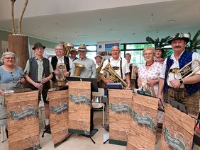Die elf Musikerinnen und Musiker der Labertaler Danzlmusi spielen im Foyer des Klinikums St. Elisabeth bayerische Blasmusik. Sie tragen traditionelle Tracht und musizieren mit Klarinetten, Trompeten, Tuben und Ziehharmonikas. Ihr Auftritt sorgt bei Patientinnen, Patienten und Besuchenden für gute Stimmung.