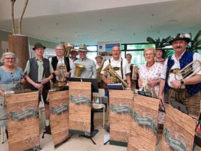 (©Ursula Urban) Die elf Musikerinnen und Musiker der Labertaler Danzlmusi spielen im Foyer des Klinikums St. Elisabeth bayerische Blasmusik. Sie tragen traditionelle Tracht und musizieren mit Klarinetten, Trompeten, Tuben und Ziehharmonikas. Ihr Auftritt sorgt bei Patientinnen, Patienten und Besuchenden für gute Stimmung.