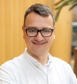 Portrait von lächelndem Arzt mit braunen Haaren und schwarzer Brille