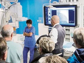 Foto vom Rundgang im Herzkatherlabor mit Besuchern und Pflegemitarbeiterin